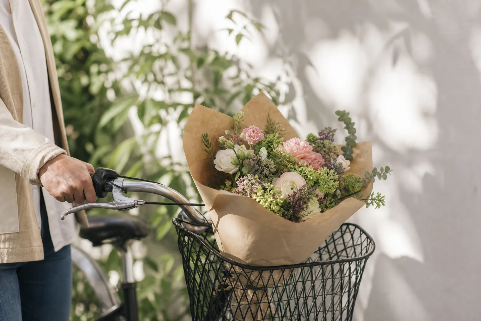 Bukett med snittblommor inslagen i papper mot neutral bakgrund.