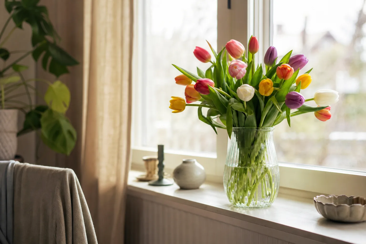 Bukett med säsongsblommor bunden i papper, placerad på ett bord.