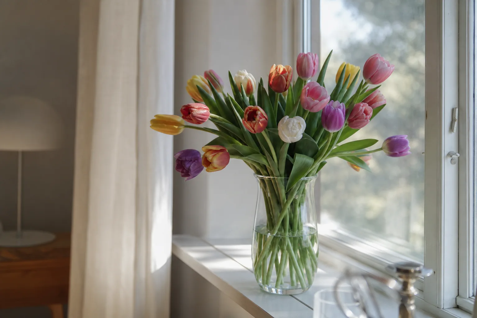 Bukett med säsongens snittblommor i vitt och rosa, nyinpackad inför leverans.